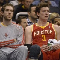 Houston Rockets forward Tim Ohlbrecht, left, watches from the bench with Omer Asik (3)